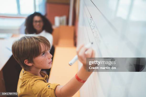 schoolboy solving maths on whiteboard - algebra stock pictures, royalty-free photos & images