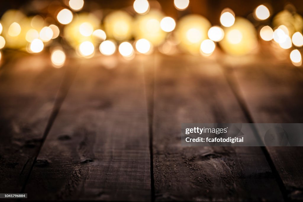 Empty rustic wooden table with blurred Christmas lights at background