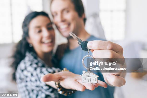 couple cheerful home owners holding a key - moving house stock pictures, royalty-free photos & images