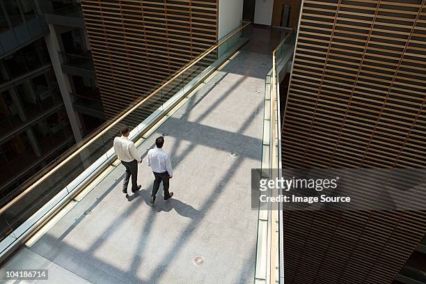 businessmen on office walkway - office elevated view stock pictures, royalty-free photos & images