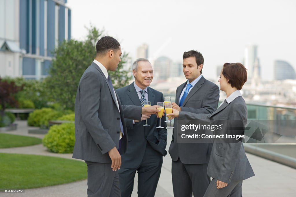 Businesspeople outdoors toasting with bucks fizz