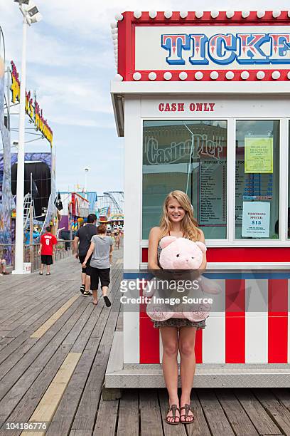 teenage girl by ticket booth with teddy bear - boardwalk stockfoto's en -beelden
