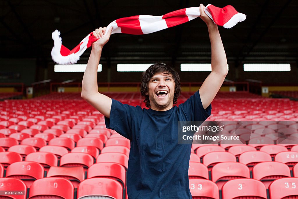 Happy football fan in empty stadium