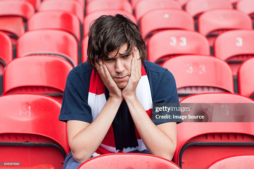 Disappointed football fan in empty stadium