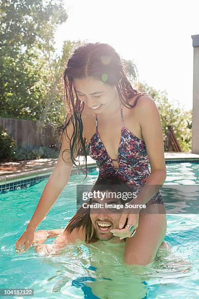 young woman on young man's shoulders in swimming pool - hollywood couples stock pictures, royalty-free photos & images