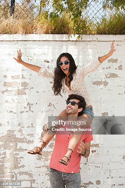 young man with young woman on shoulders - hollywood couples stock pictures, royalty-free photos & images