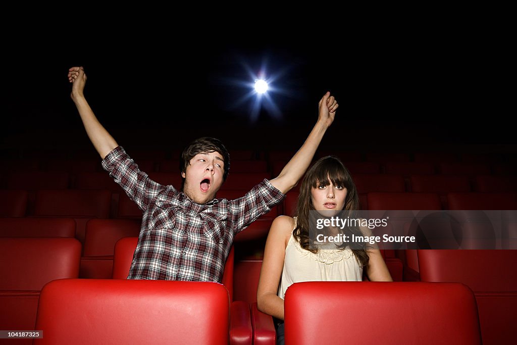 Menino adolescente mãos bocejo no cinema