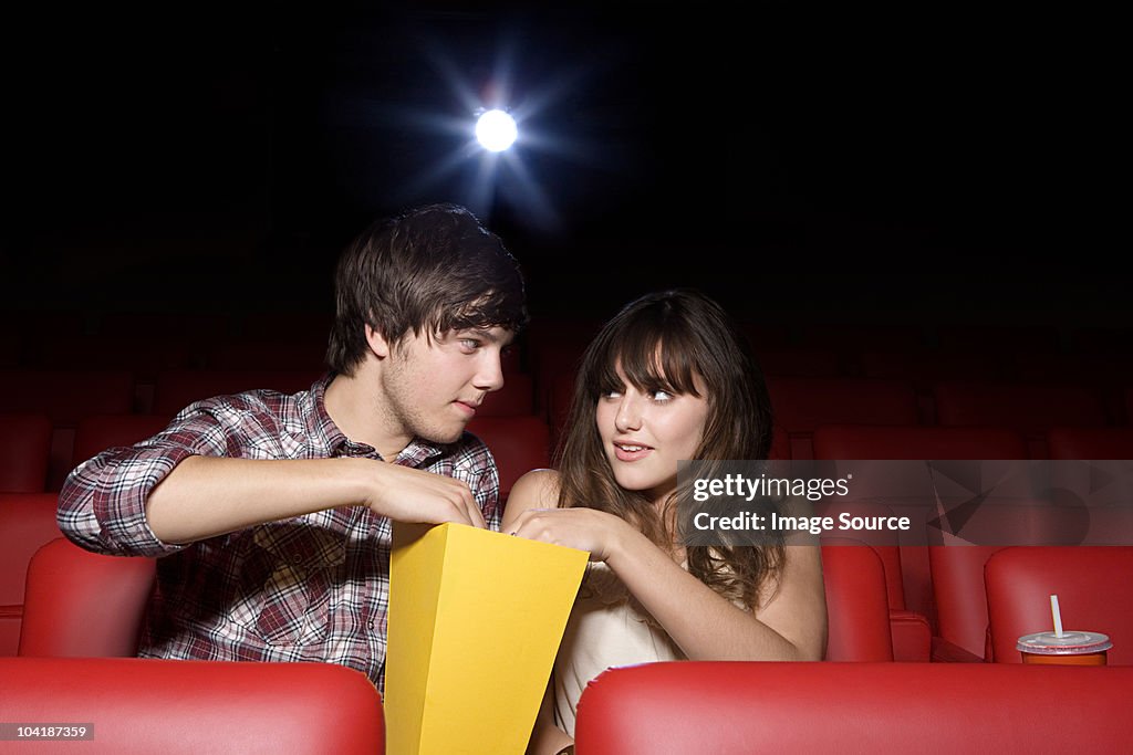 Young couple sharing popcorn in movie theater