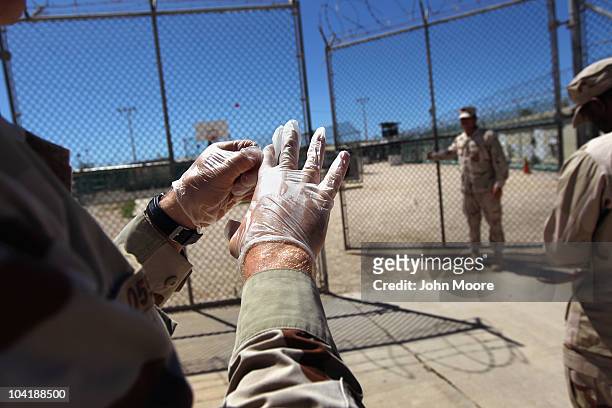 Military guard puts on rubber gloves before moving an "enemy combatant" within the detention center on September 16, 2010 in Guantanamo Bay, Cuba....