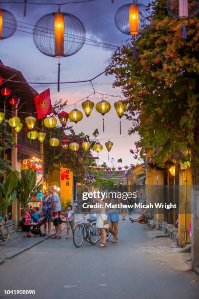june 2017 hoi an, vietnam - tourists walk down the colonial streets in historic old town hoi an. lanterns illuminate the walkways. - hoi an stockfoto's en -beelden