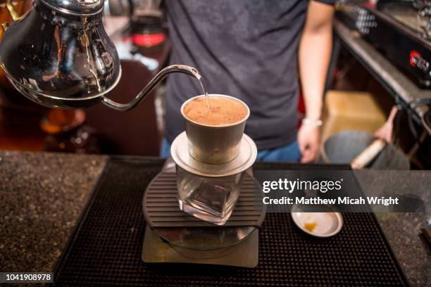 june 2017 hoi an, vietnam - a local man pour fresh coffee from his craft coffee shop. - vietnamese culture stock pictures, royalty-free photos & images