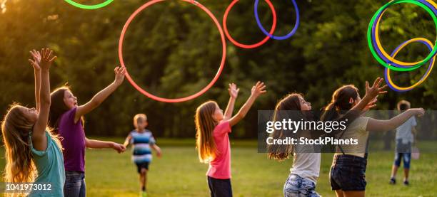 kids throwing a plastic hoops in the park - school vacation stock pictures, royalty-free photos & images