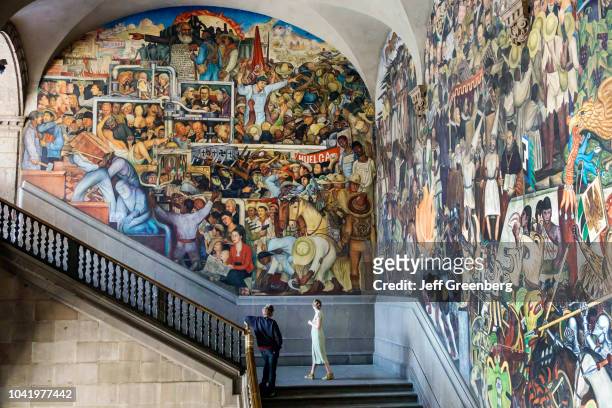 Man and woman looking at the mural on the central stairway at the National Presidential Palace.