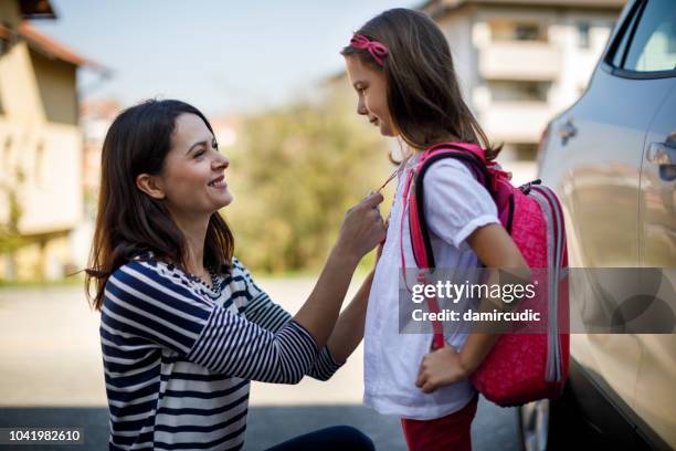 mother preparing her child for school in front of their house - back to school mom stock pictures, royalty-free photos & images