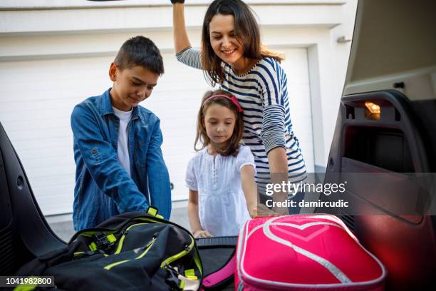 mother and children loading school backpacks into car - driving kid to school stock pictures, royalty-free photos & images