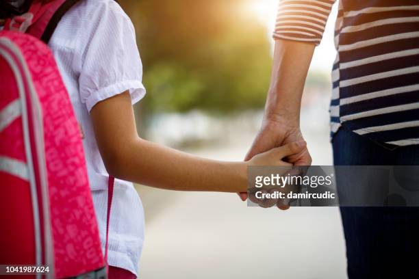 mother and daughter holding hands - leaving school imagens e fotografias de stock