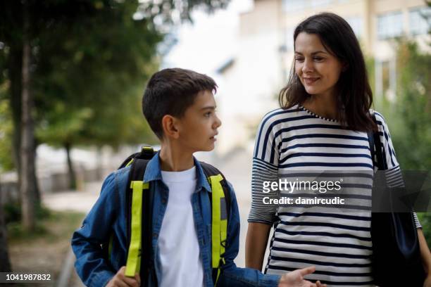 mother and teenage boy going home from school - walking boy school stock pictures, royalty-free photos & images
