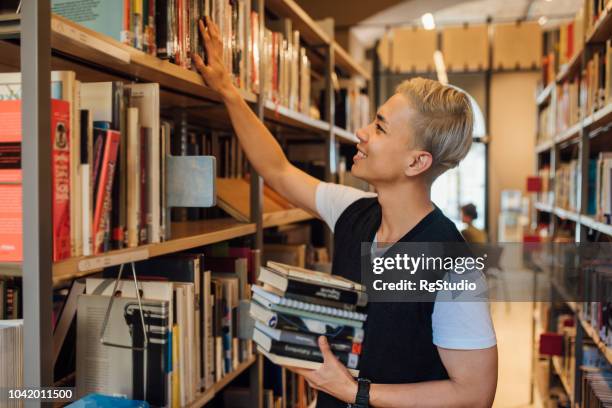 young man looking at book shelves - librarian stock pictures, royalty-free photos & images