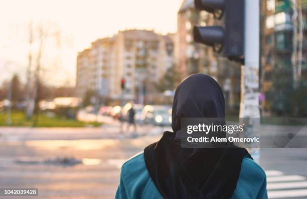 muslim woman waiting green light to cross the street - purdah stock-fotos und bilder