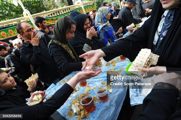 Volunteers hand out bread, potatoes, and tea as Iranians mark the anniversary of the 7th-century death of the third Shiite Imam Hossein, with day and...