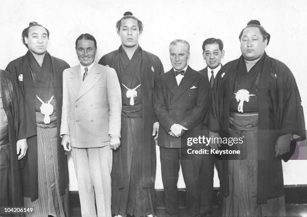 Comic actor Charlie Chaplin and his elder half-brother Sydney with Japanese Sumo wrestlers, during a holiday in Japan, 1932.