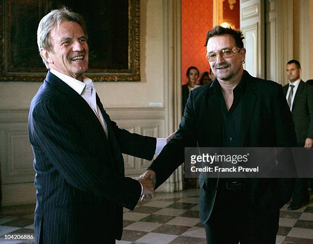 French Foreign Minister, Bernard Kouchner shakes hands with lead singer Bono of Irish rock band U2 at Quai d'Orsay on September 17, 2010 in Paris,...