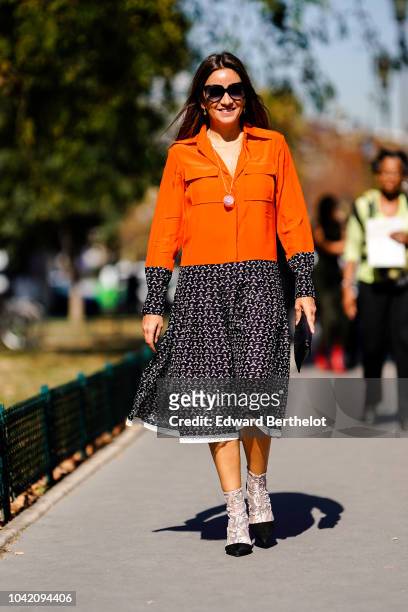 Guest wears an orange jacket, a black and white skirt, outside Paco Rabanne, during Paris Fashion Week Womenswear Spring/Summer 2019, on September...
