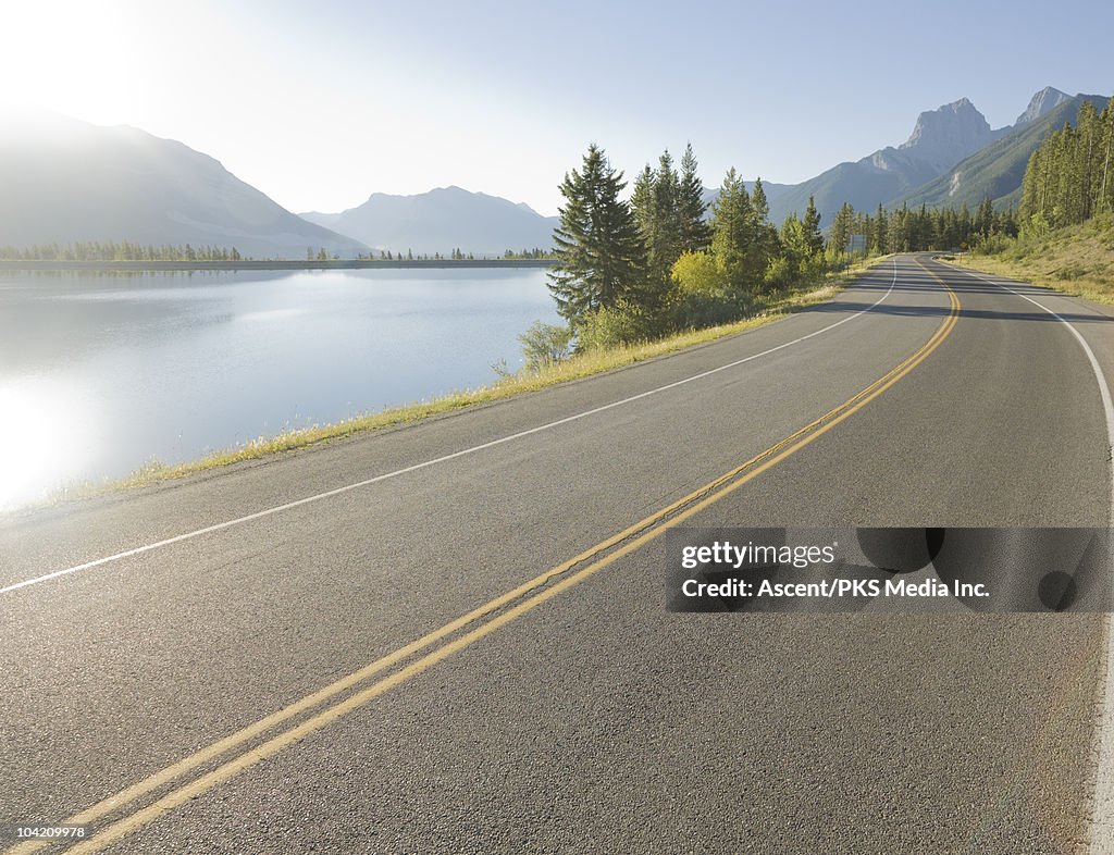 Mountain road curves around lake, in mountains