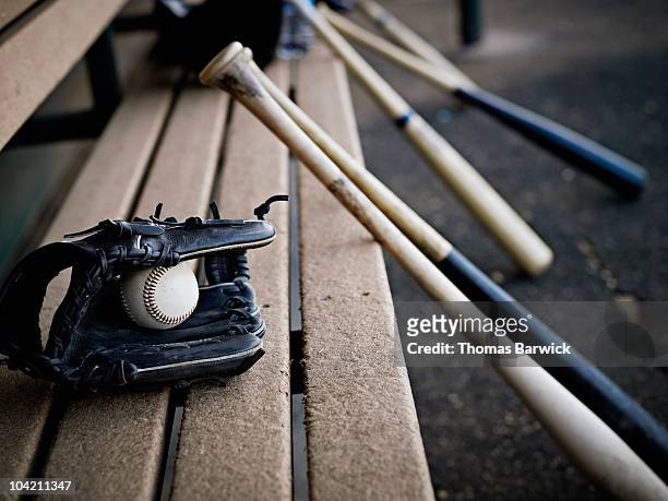 baseball glove with ball and bats in dugout - baseball equipment stockfoto's en -beelden