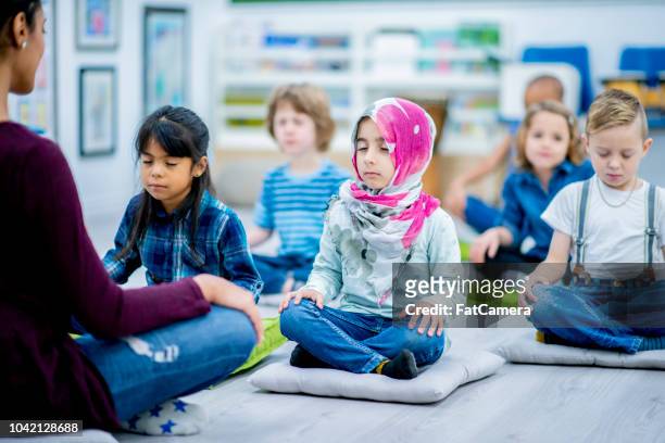 élèves de la maternelle méditent en classe - yoga rug photos et images de collection