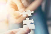 Hand of two people holding jigsaw puzzle connecting together. Concept of partnership and teamwork in business strategy