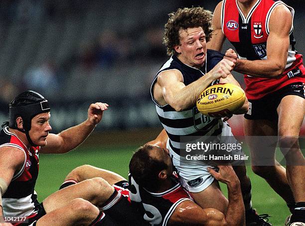 Gary Hocking for Geelong, attempts to handball to a team mate, despite being tackled by Stuart Lowe for St. Kilda, during the round 17 AFL game...