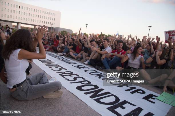 Students seen sitting down with their hands raised next to banners and posters in front of the university rectory during a strike by students of the...