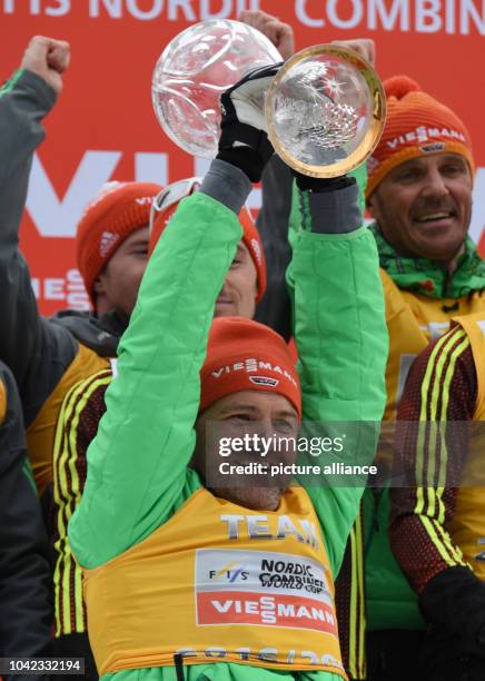 The German national trainer Hermann Weinbuch holds the crystal ball trophy after his team's victory in the men's 10km cross-country on the large hill...