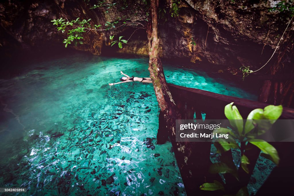 Woman swimming in a cenote around Tulum, Quintana Roo,...