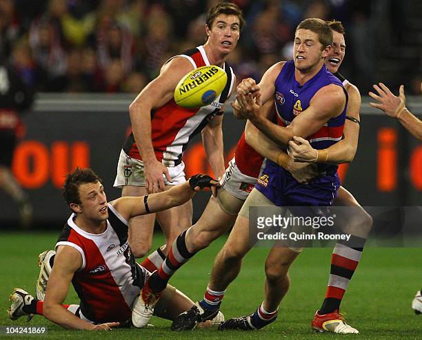 Callan Ward of the Bulldogs handballs whilst being tackled by Brendon Goddard of the Saints during the Second AFL Preliminary Final match between the...