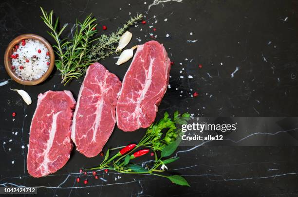 steaks crus sur marbre - viande fond noir photos et images de collection
