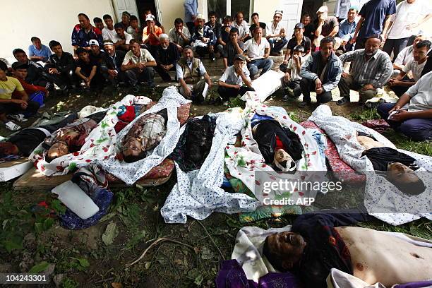 Uzbek residents sit in front of bodies of the victims of the violent clashes in the suburb of Osh, on June 13, 2010. Tens of thousands of refugees...