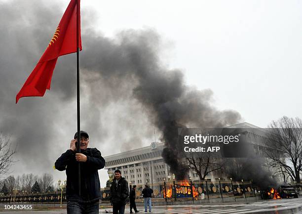 Kyrgyz opposition supporter waves the national flag near the main government building during an anti-government protest in Bishkek on April 7, 2010....