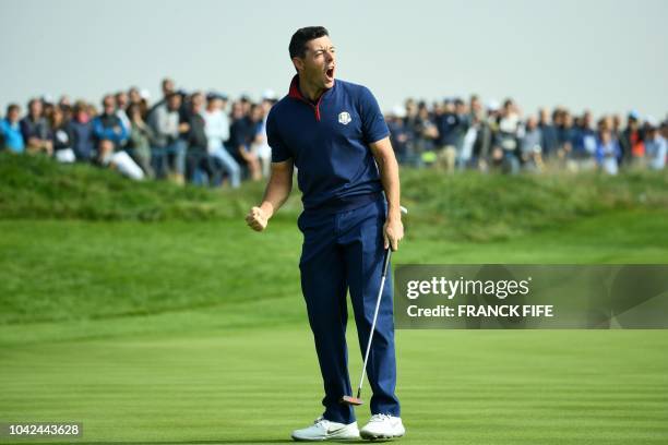 Europe's Northern Irish golfer Rory McIlroy reacts after making a putt during his foursomes match on the first day of the 42nd Ryder Cup at Le Golf...