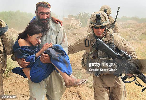 Marines help as a young girl is carried by her father to a MEDEVAC helicopter September 18, 2010 near Marja, Afghanistan. The girl suffered wounds to...