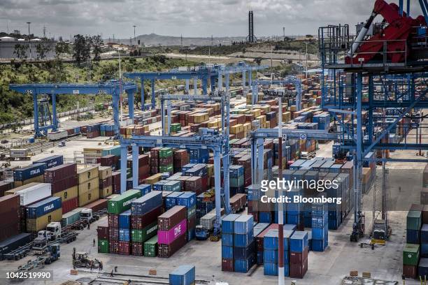 Shipping containers stand beneath gantry cranes on the dock at Mombasa port, operated by Kenya Ports Authority, in Mombasa, Kenya, on Saturday, Sept....
