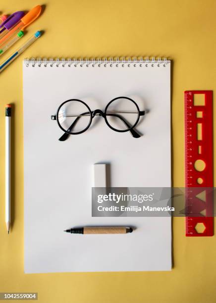 anthropomorphic face made of school supplies on table - reading glasses on table stock pictures, royalty-free photos & images