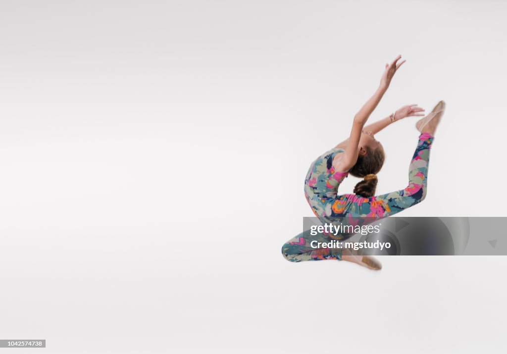 Beautiful gymnast athlete teenage girl jumping in studio