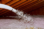 Spraying Blown Fiberglass Insulation for roof - technician spraying foam insulation using plural component gun