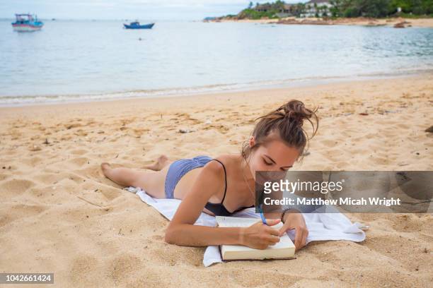 a woman sits on the beach and writes in her diary in bai xep; a quiet remote fishing village off the tourist path, 10km from the major city of qui nhon. - trip diary stock pictures, royalty-free photos & images