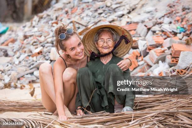 a young tourist stops to meet and laugh with an elderly local woman who is hard at work in the village of bai xep. - vietnam woman stock pictures, royalty-free photos & images