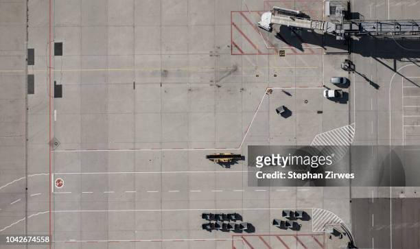 view from above airport service vehicles and passenger boarding bridge on tarmac at airport - tarmac stockfoto's en -beelden