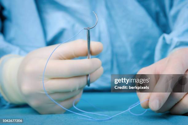 close up surgeon holding needle - surgeon holding needle stock-fotos und bilder
