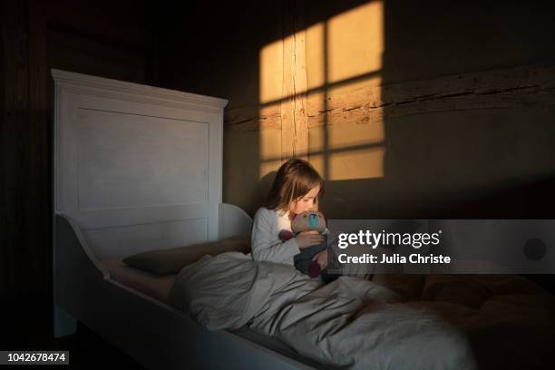 girl hugging teddy bear in bed - stofftier stock-fotos und bilder